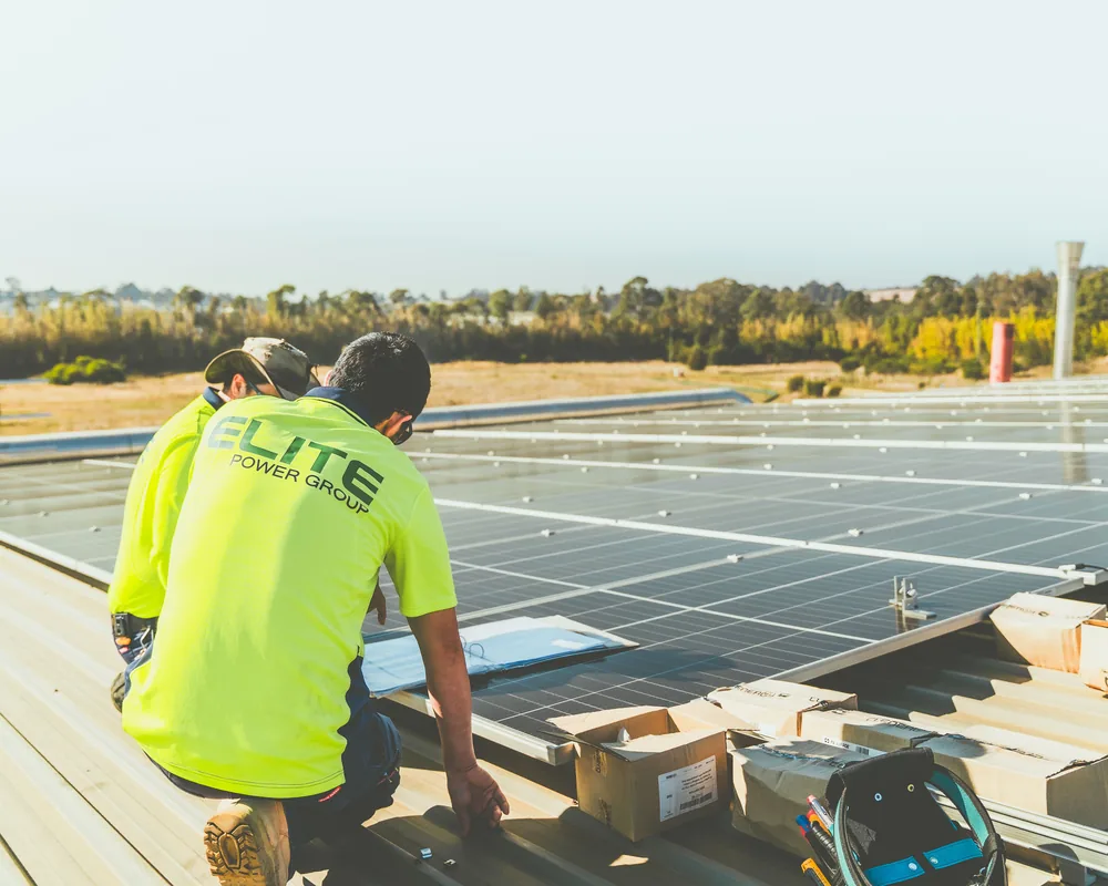 Técnicos instalando painéis solares em telhado comercial